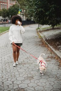 black woman drinking coffee while walking dog Photo by Samson Katt on Pexels.com